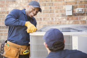 smiling-HVAC-technician-working-on-ac-oudoor-unit